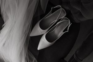 A collection of white high heeled shoes arranged in a row against a dark background.
