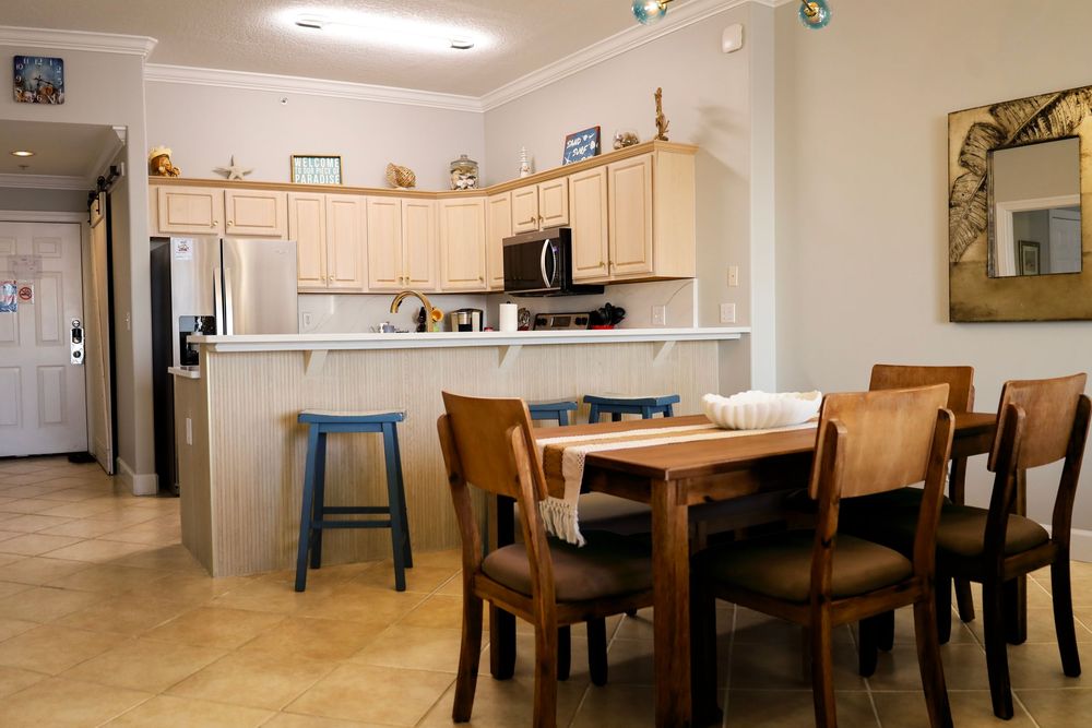 A panoramic view of a modern open-concept kitchen and dining area with light wood cabinets and dark furniture.