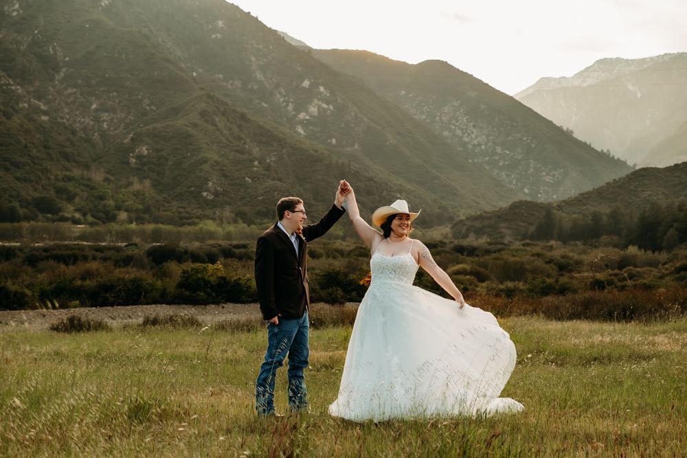 Couple standing facing each other with mountains in the background.