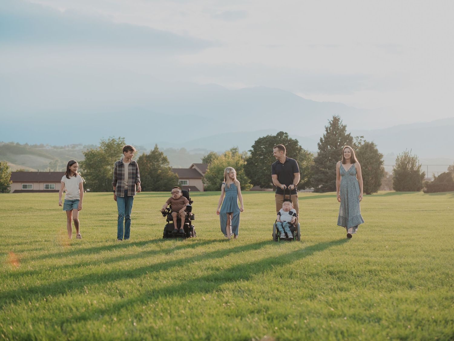 People gathered in a grassy field on a sunny day creating a panoramic scene.