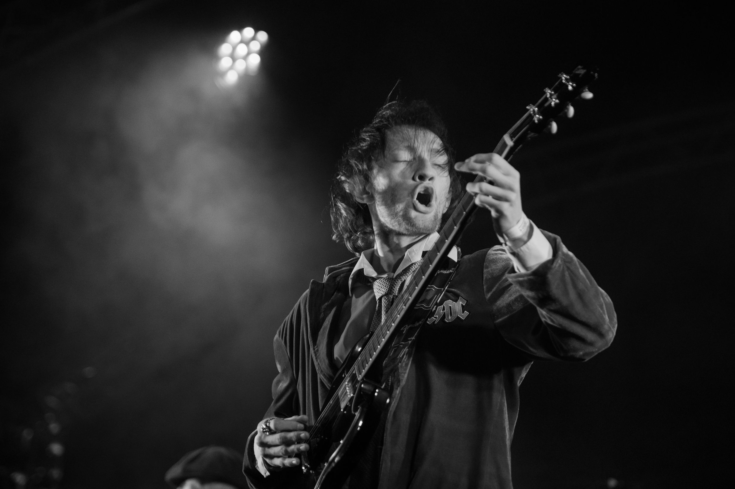 Black and white photo of a musician performing on stage with dramatic lighting and shadows.