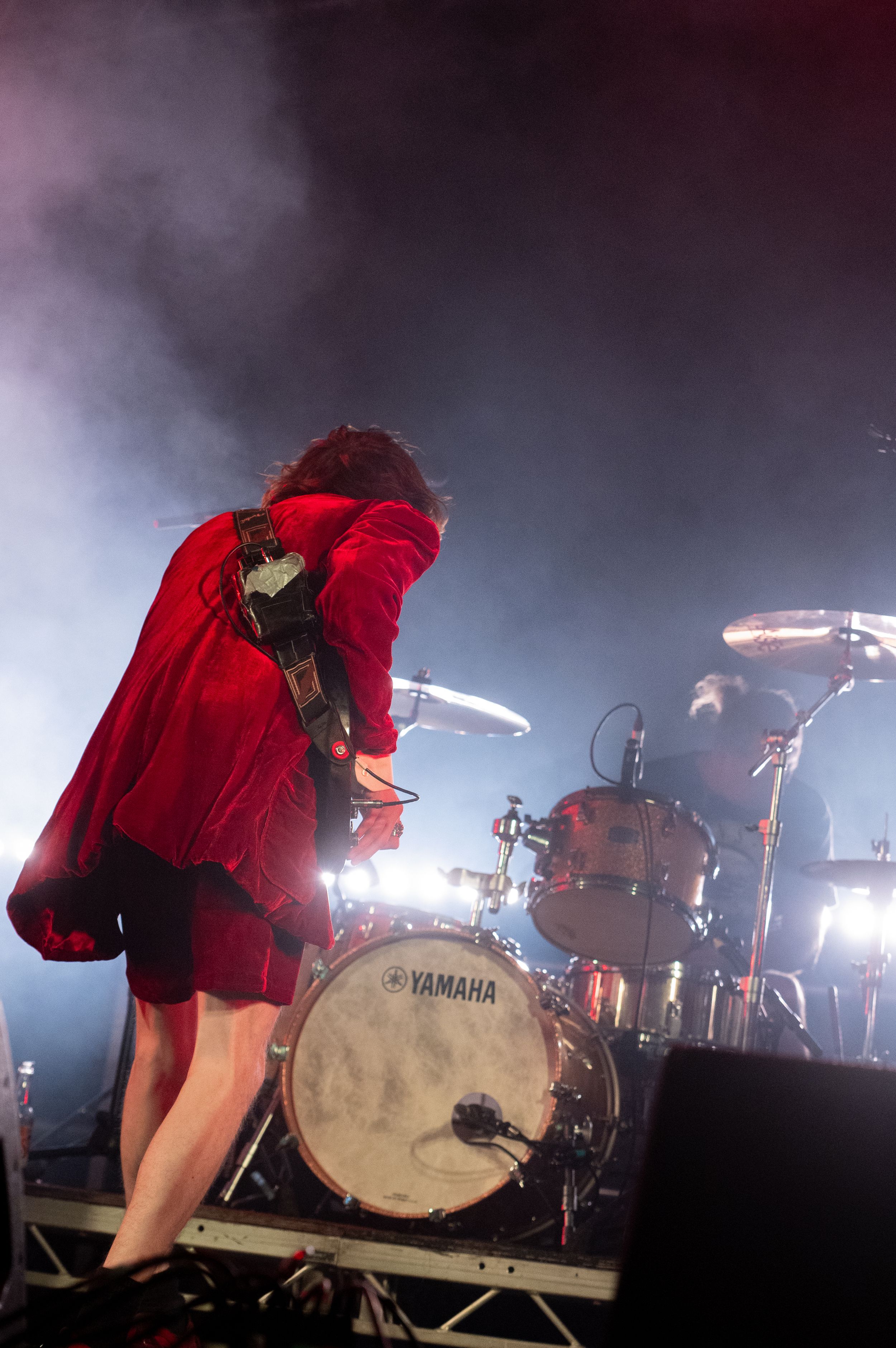 Yamaha drum kit on stage illuminated by bright stage lights with atmospheric fog effects.