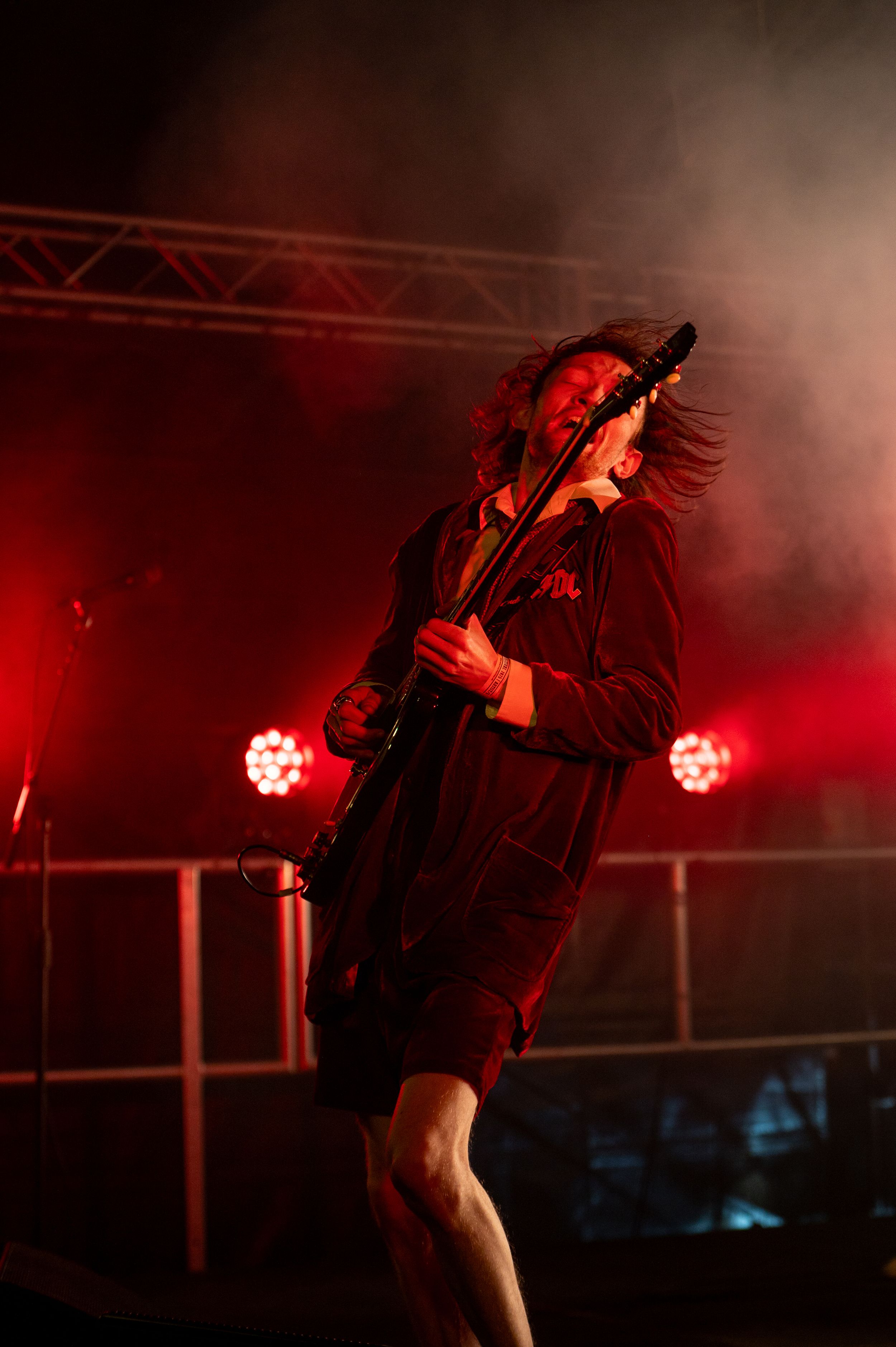 Concert performer silhouetted against red stage lighting and fog during an energetic live show.