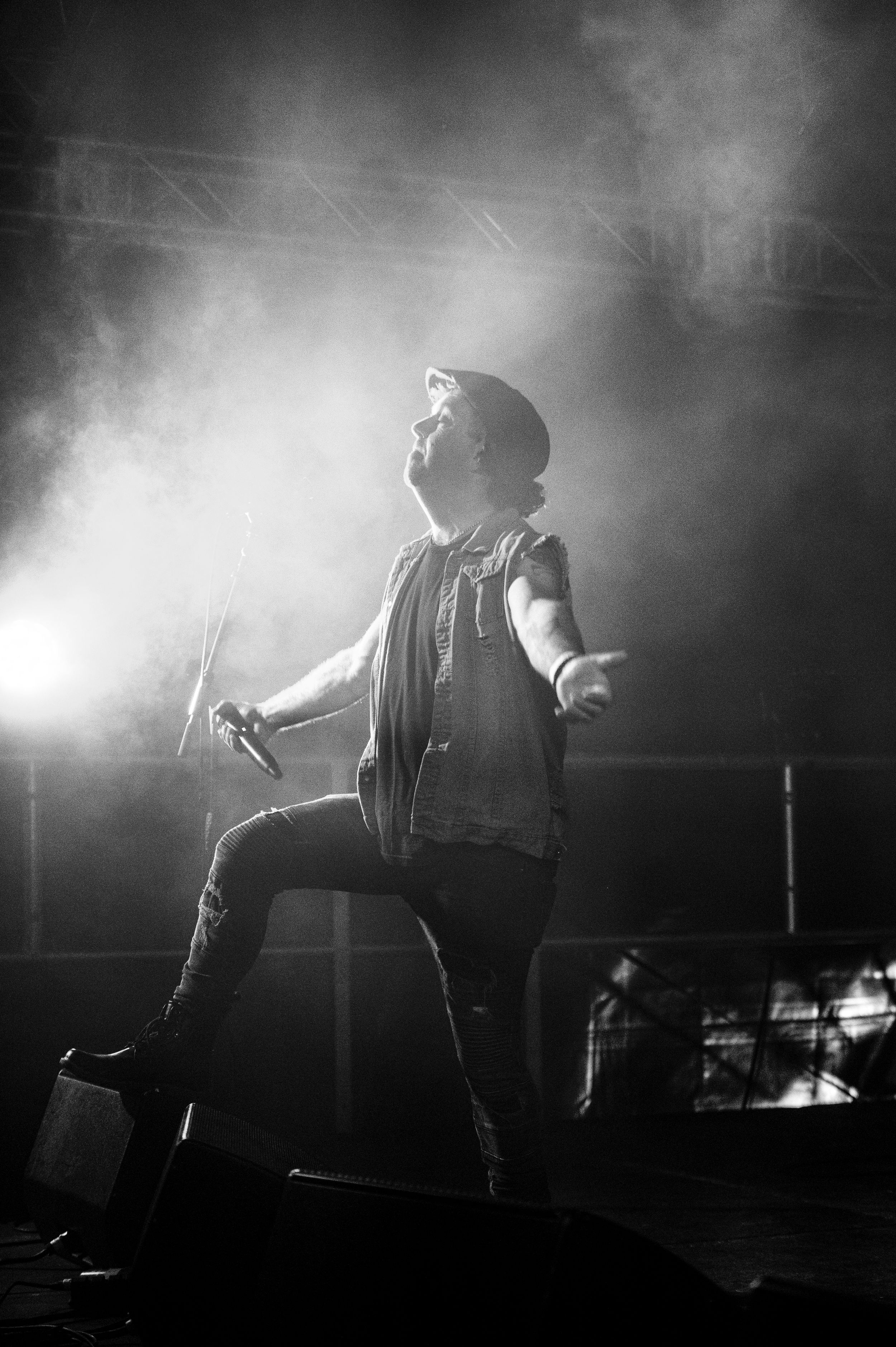 Silhouetted performer on stage captured in black and white with dramatic fog effects and lighting.