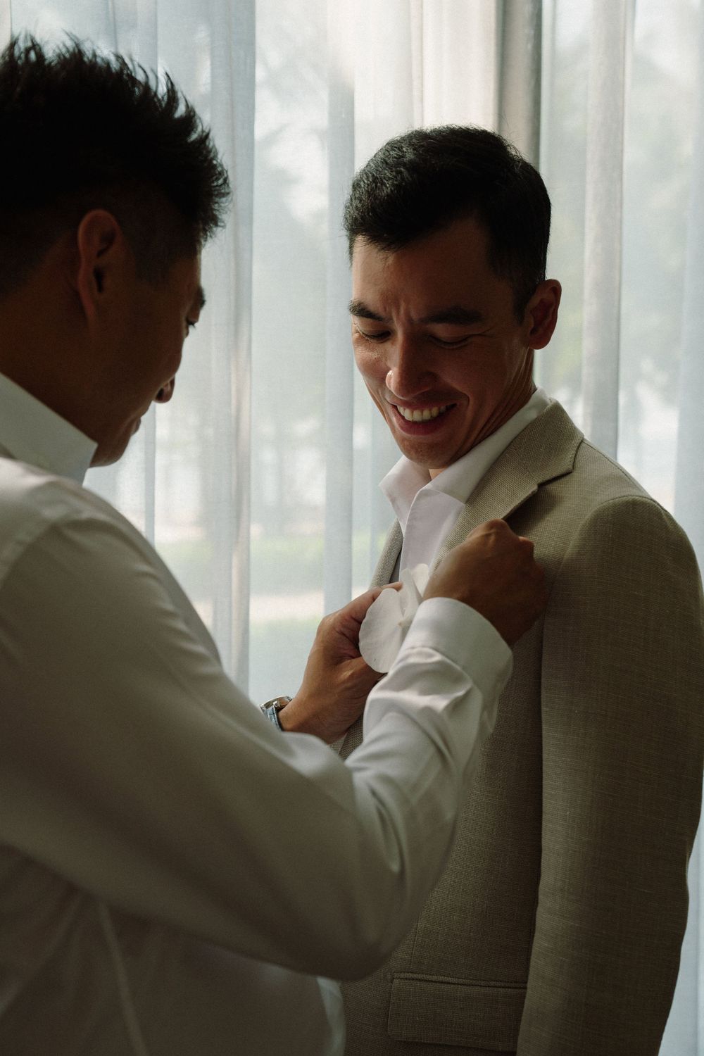 A series of candid moments showing two people in white and beige attire sharing laughter near a window.