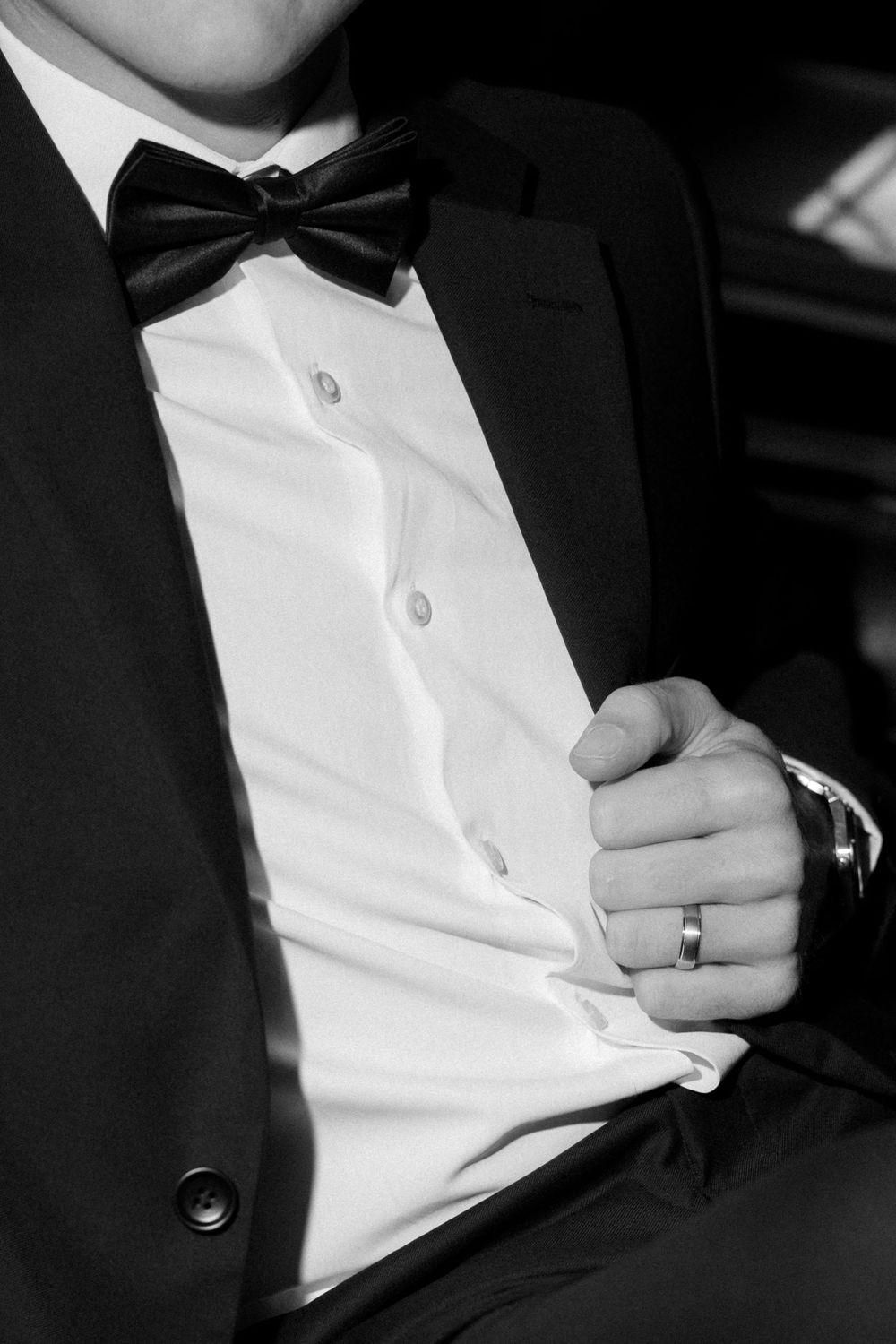 Close-up black and white detail of a tuxedo bow tie and white dress shirt.