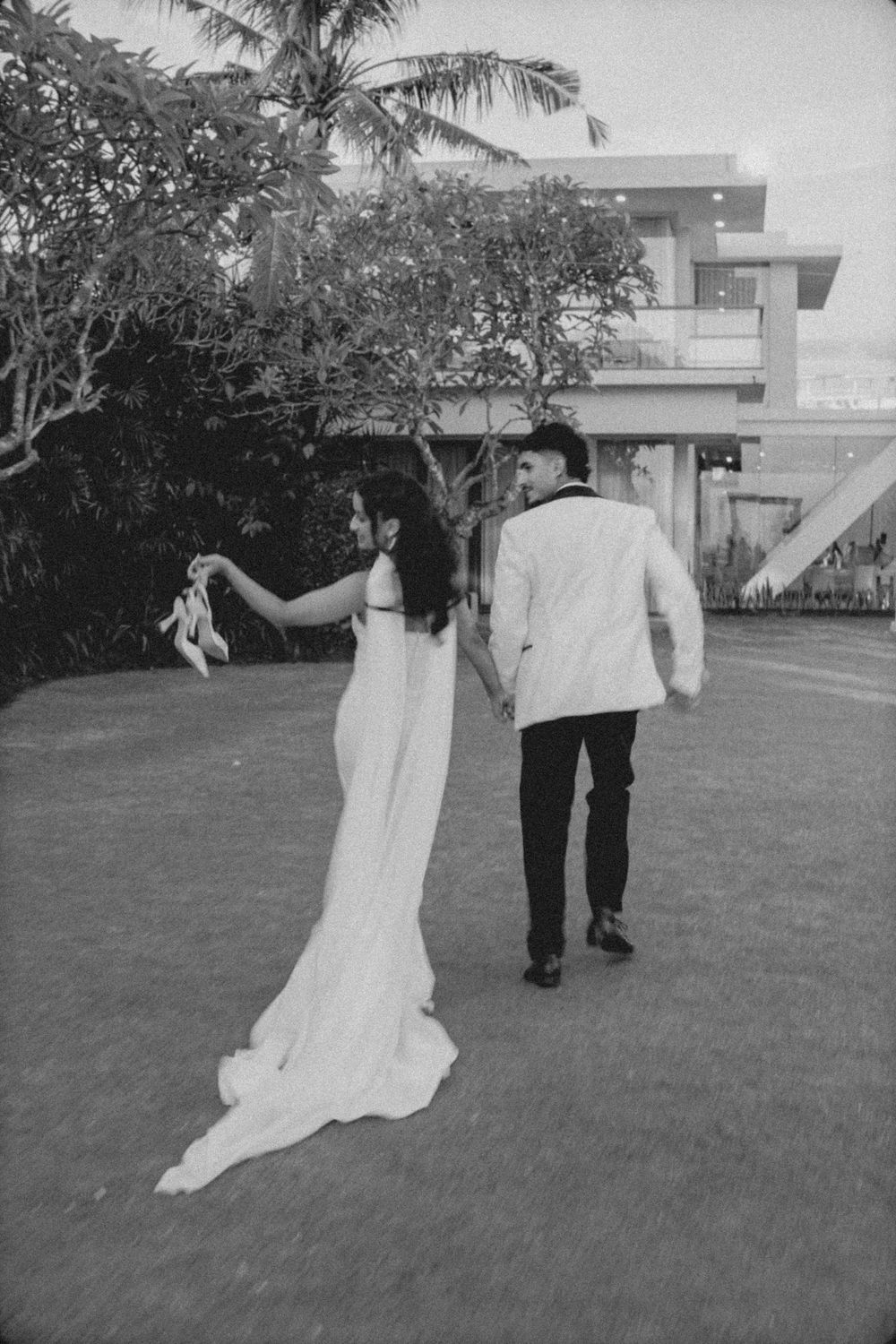 A sequence of black and white photos showing a couple walking together on a grassy lawn in wedding attire.