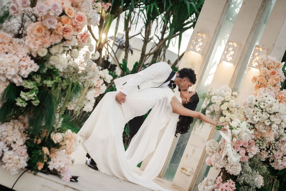 A romantic wedding scene with soft pink floral arrangements and white decor in an elegant indoor venue.