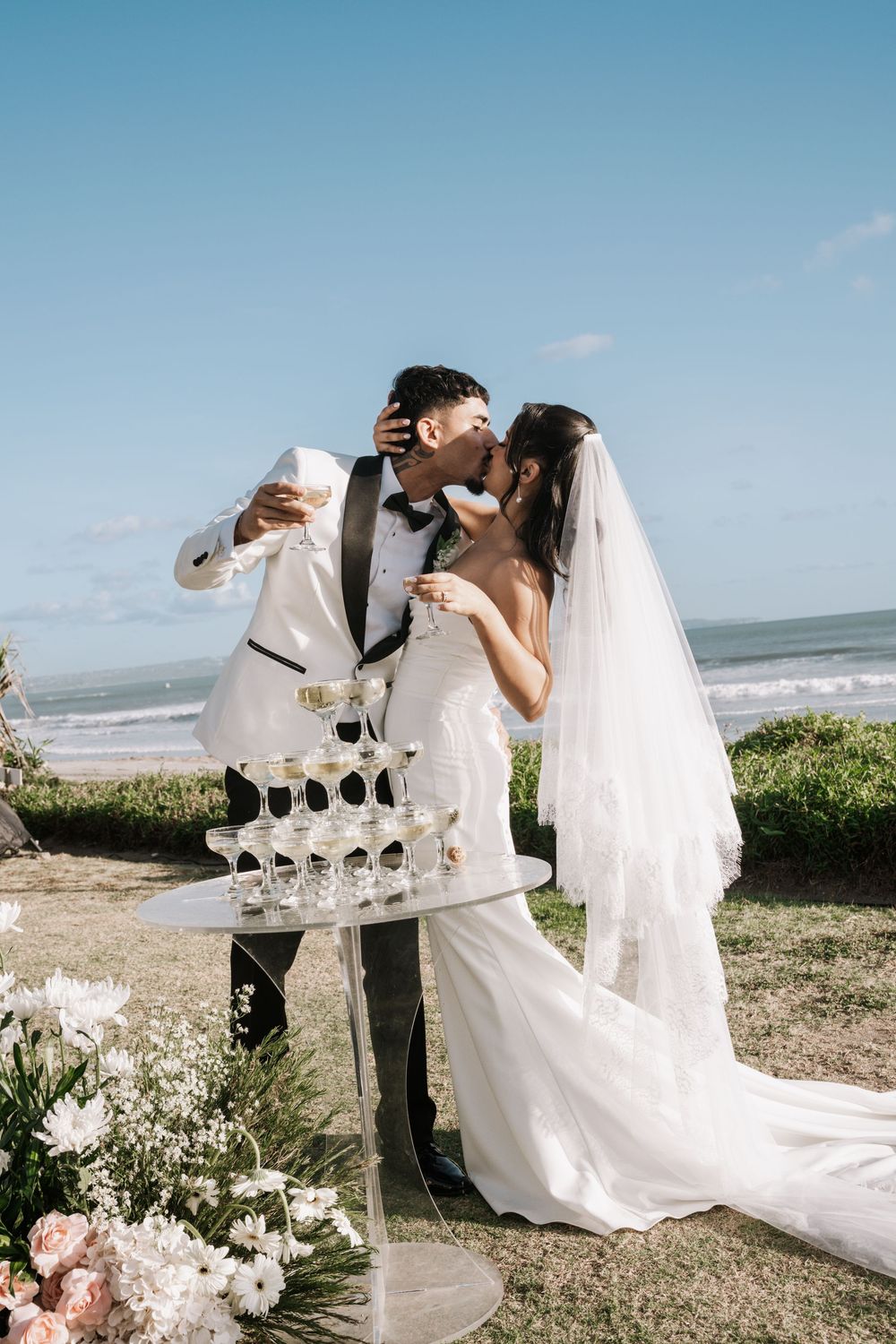 A romantic beach wedding photo series showing champagne toasts and intimate moments against an oceanfront backdrop.