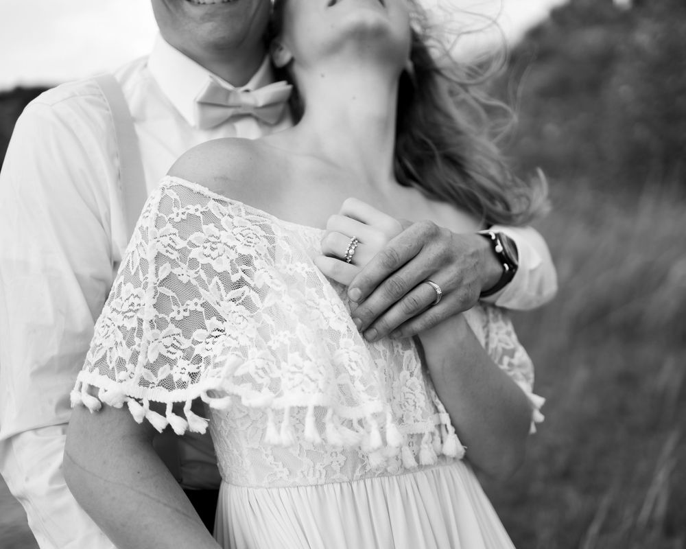A romantic black and white photo showing close embrace with lace dress details and bow tie visible.