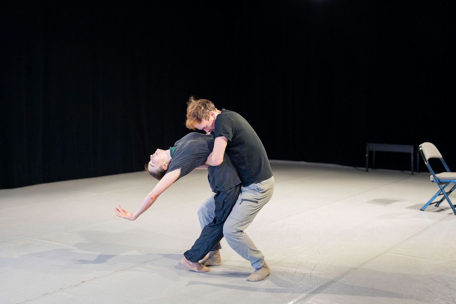 A sequence of dance movements captured in a dark studio showing a person performing a fluid floor routine.