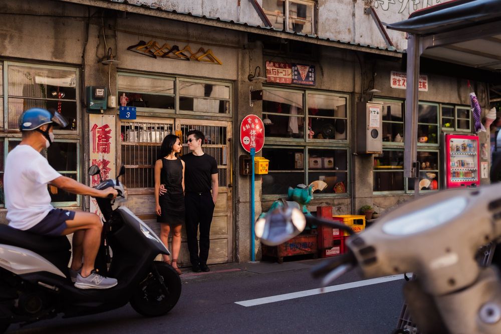 A scenic photo of a couple dressed in black in a old traditional Chinese style rustic street.