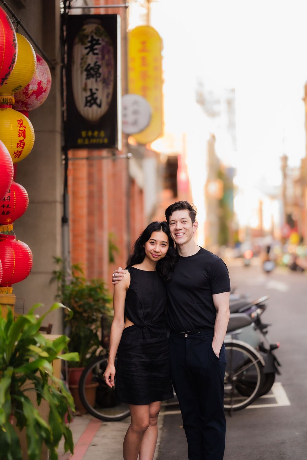 A couple poses together on Taipei's historic Dihua Street with traditional Asian decor and red lanterns.
