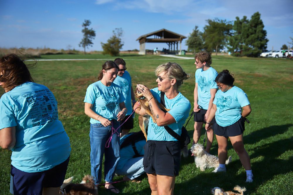 Group wearing matching blue shirts gathered at an outdoor event on a sunny day.