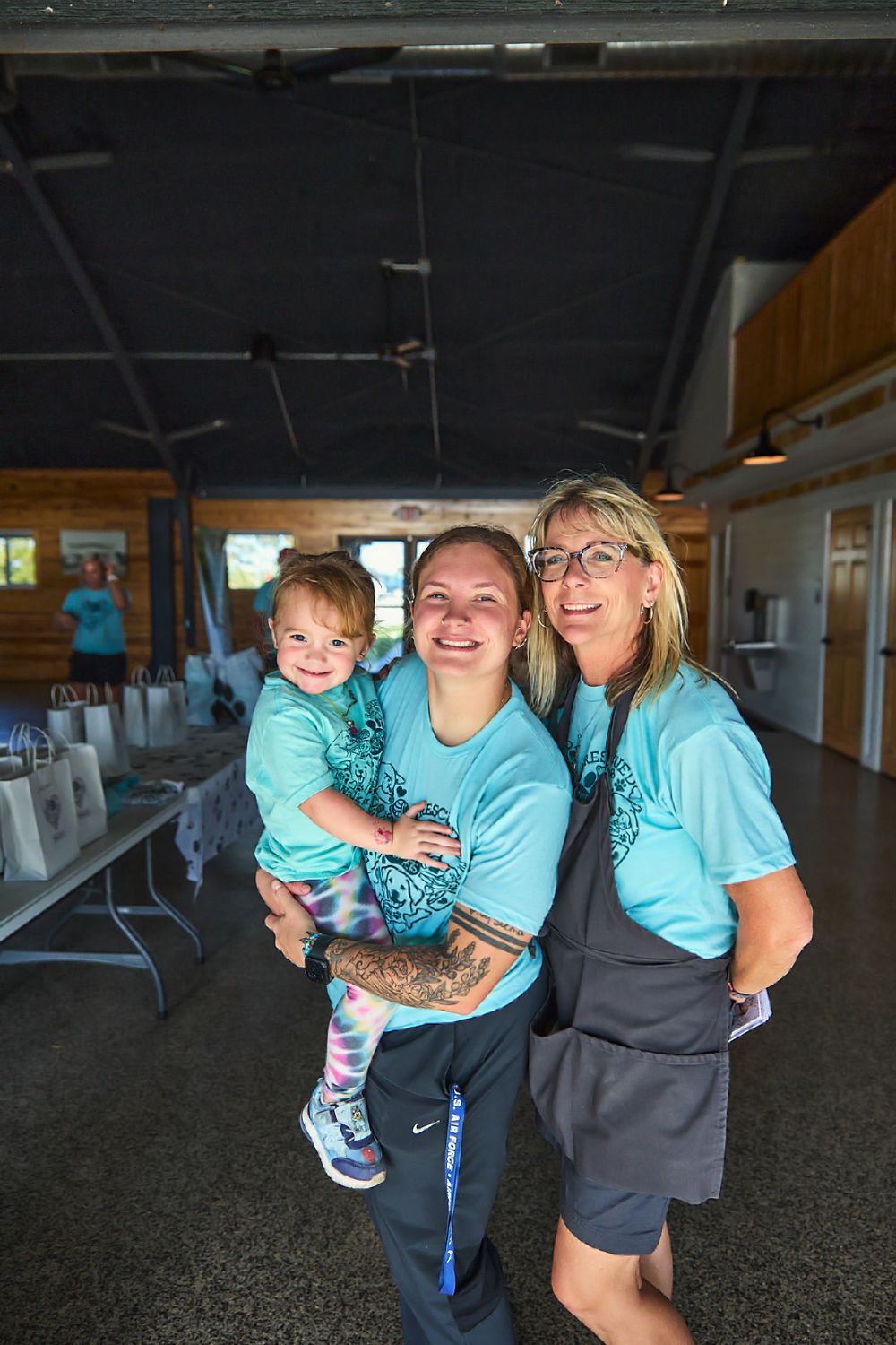 Group wearing matching turquoise shirts gathered indoors at a community event.
