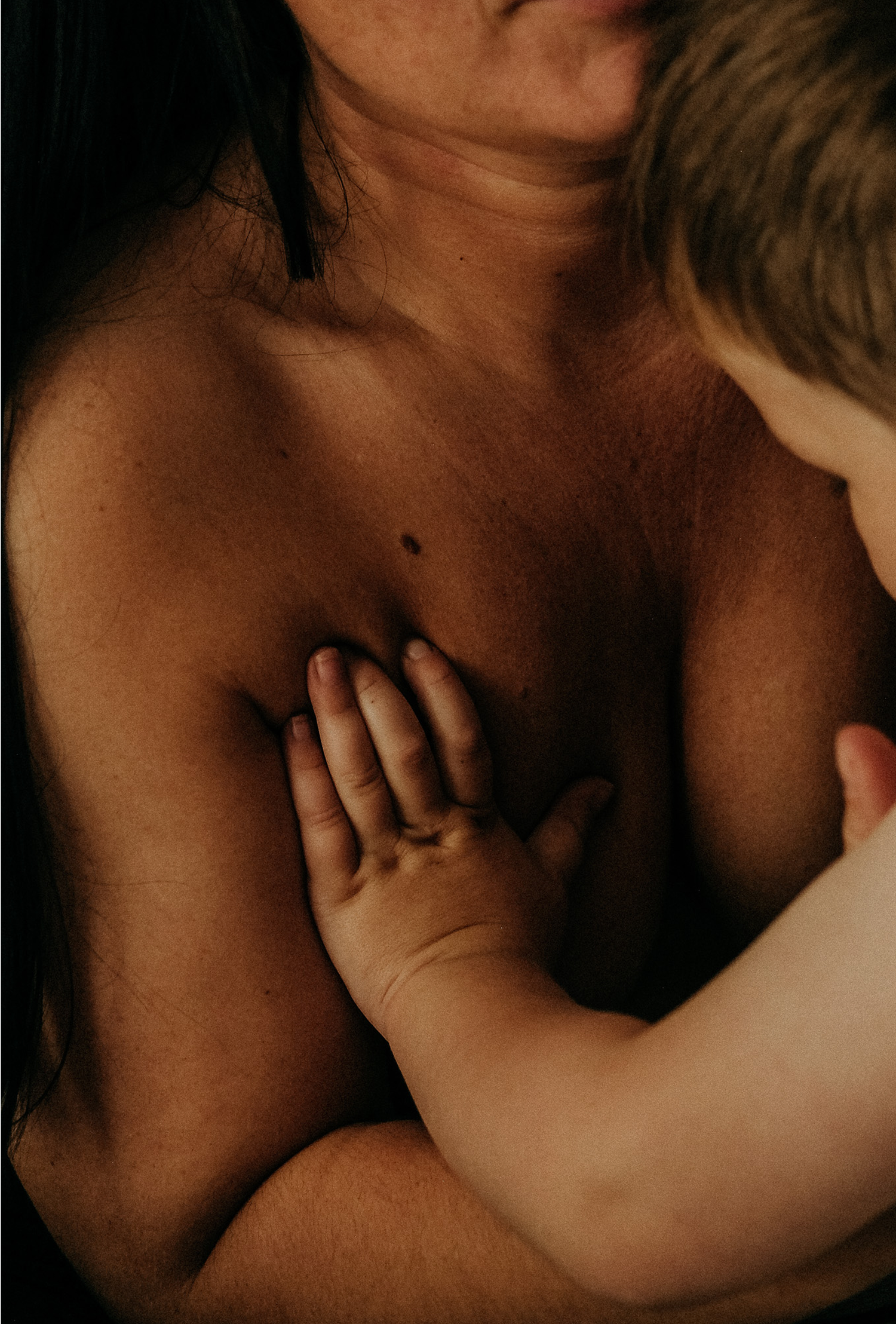 Close-up breastfeeding photo showing a child’s hand on their mother’s chest, intimate motherhood photography in Sunderland.