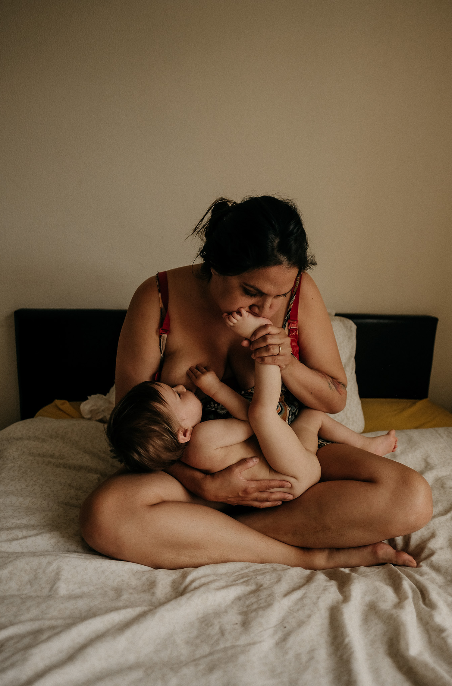 Artistic close-up breastfeeding photograph, toddler’s hand resting on mother. Emotional motherhood photography in Newcastle