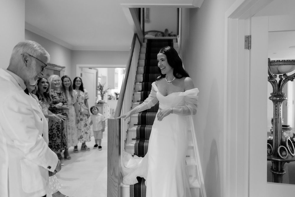 Black and white photo of wedding preparations with guests gathered in a hallway.