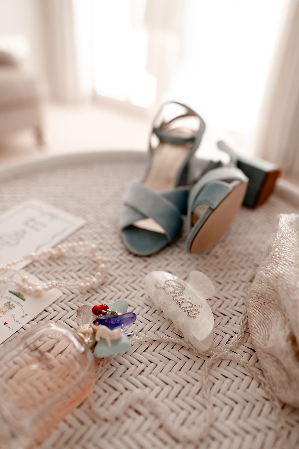 Wedding shoes and accessories arranged on a textured fabric surface.