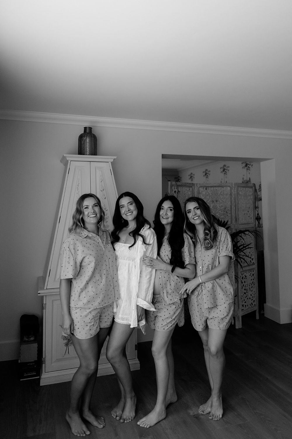 Group wearing matching floral robes posing together in a bright room.