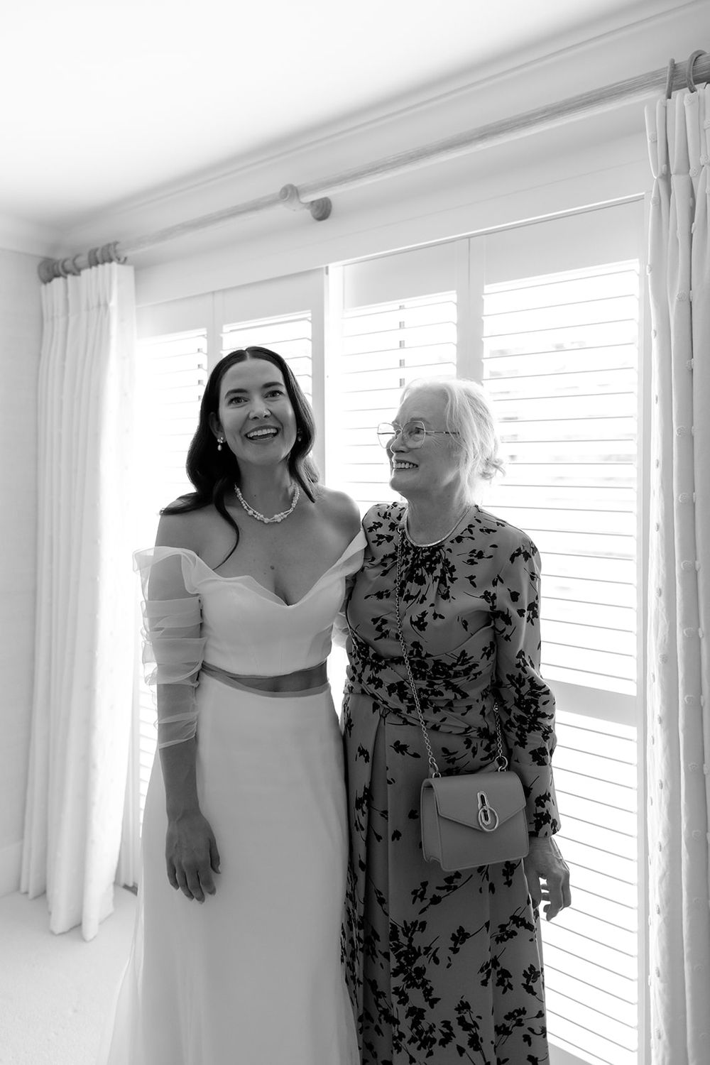 Two people sharing a joyful moment in a bright white room with window light.