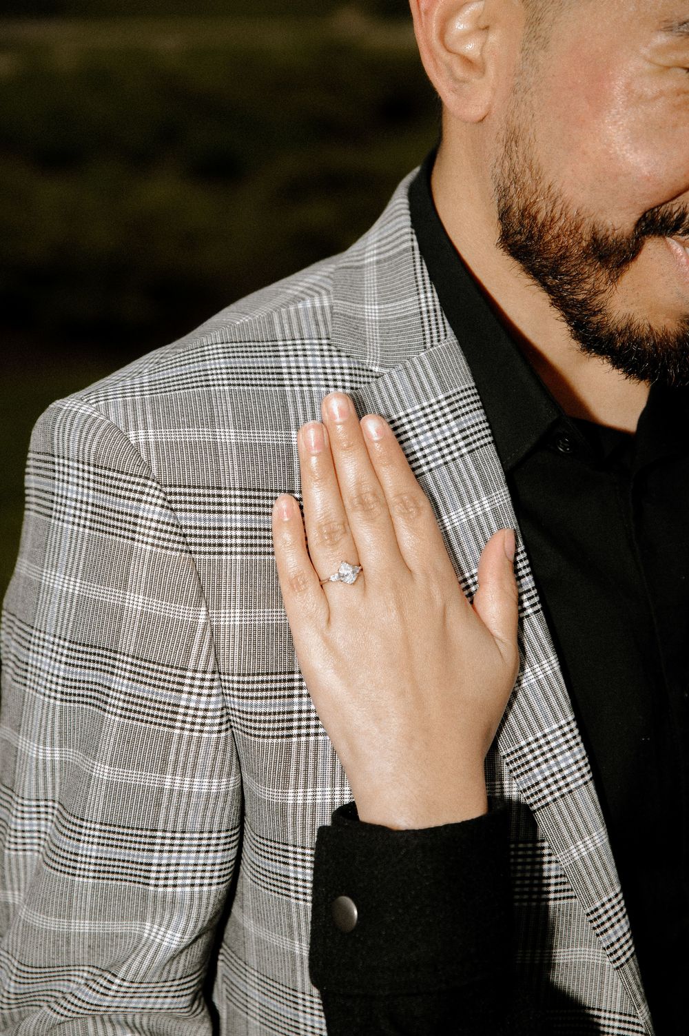 Close-up detail of an engagement ring being shown against a plaid gray and white patterned background.