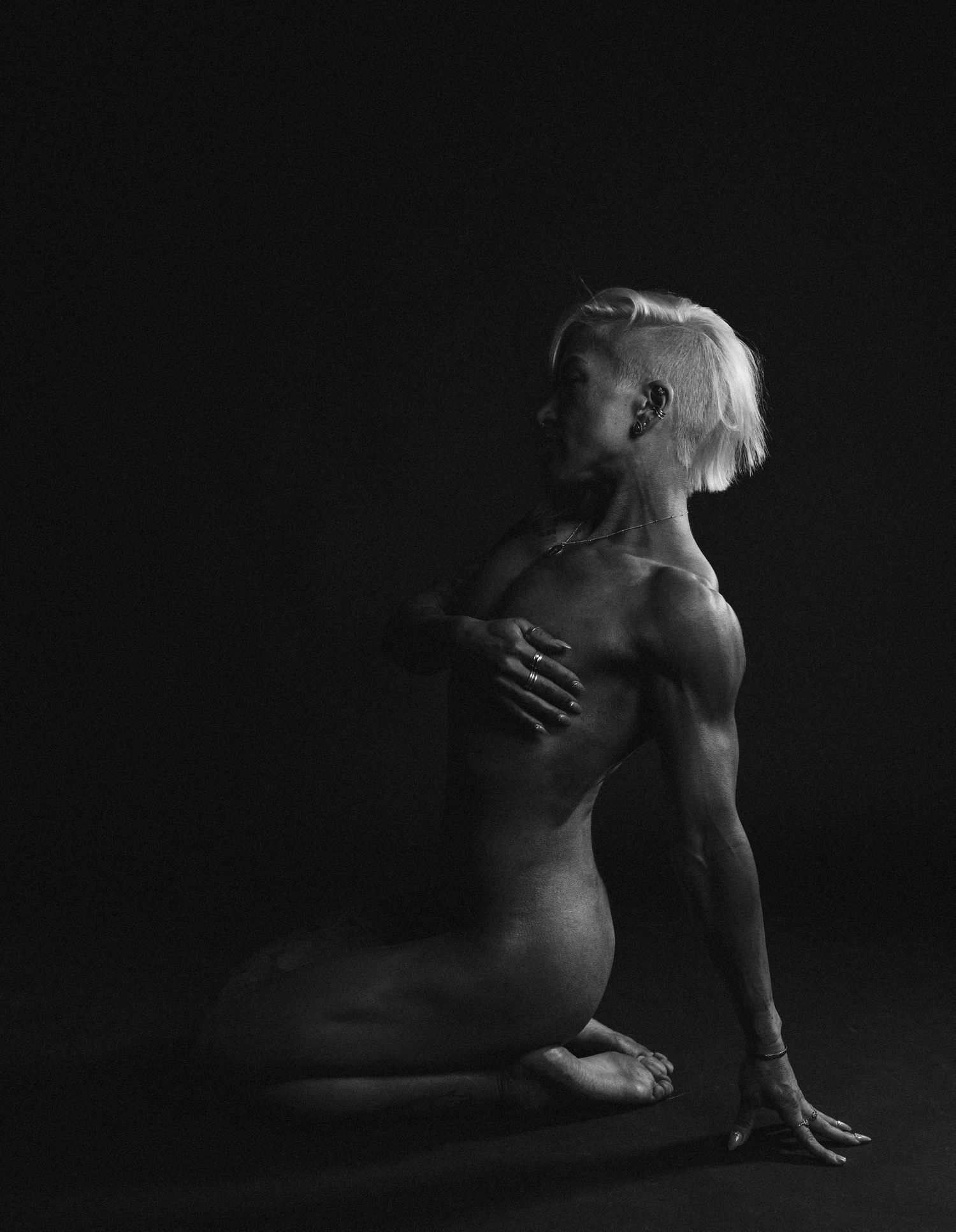 Artistic black and white nude study showing graceful body forms in dramatic lighting.