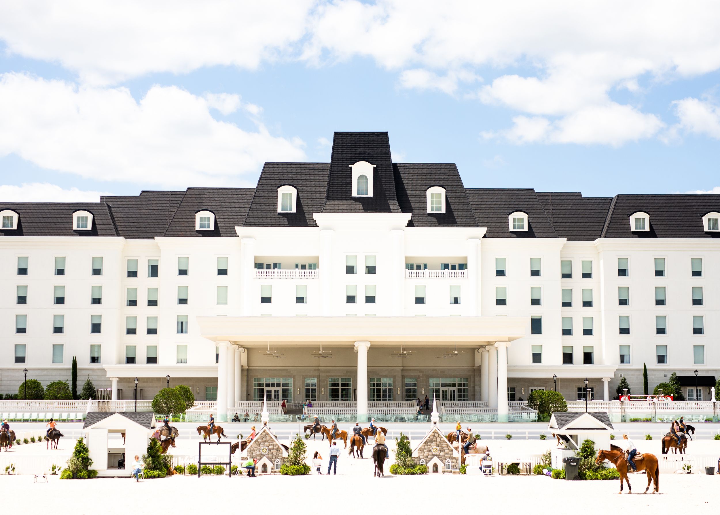 A panoramic view of a large white colonial-style hotel building with dormer windows and landscaped grounds.