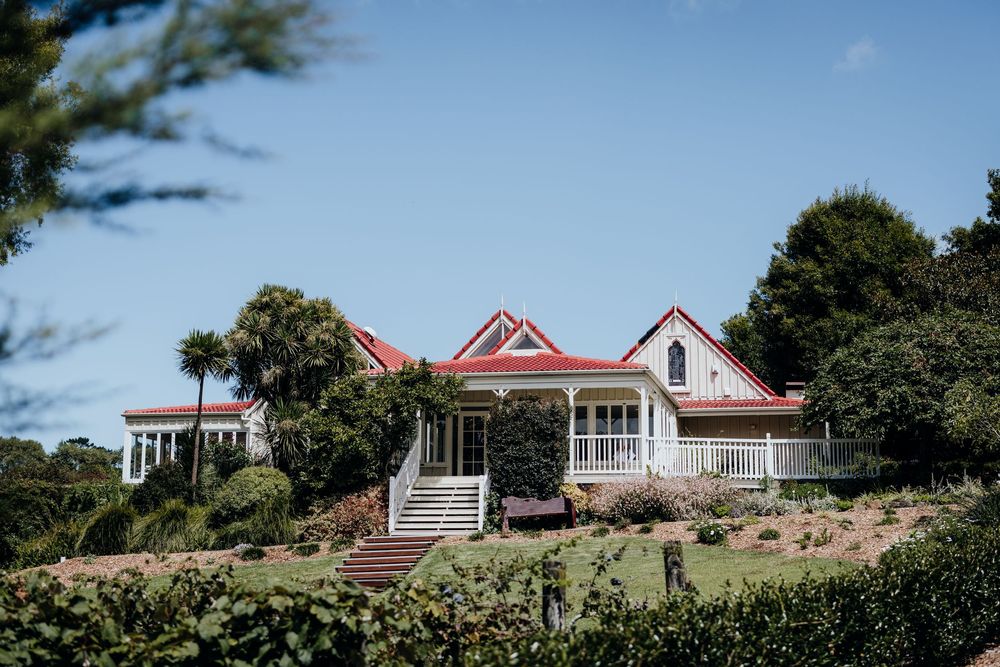 A row of charming coastal cottages with red roofs nestled among lush greenery on a hillside.