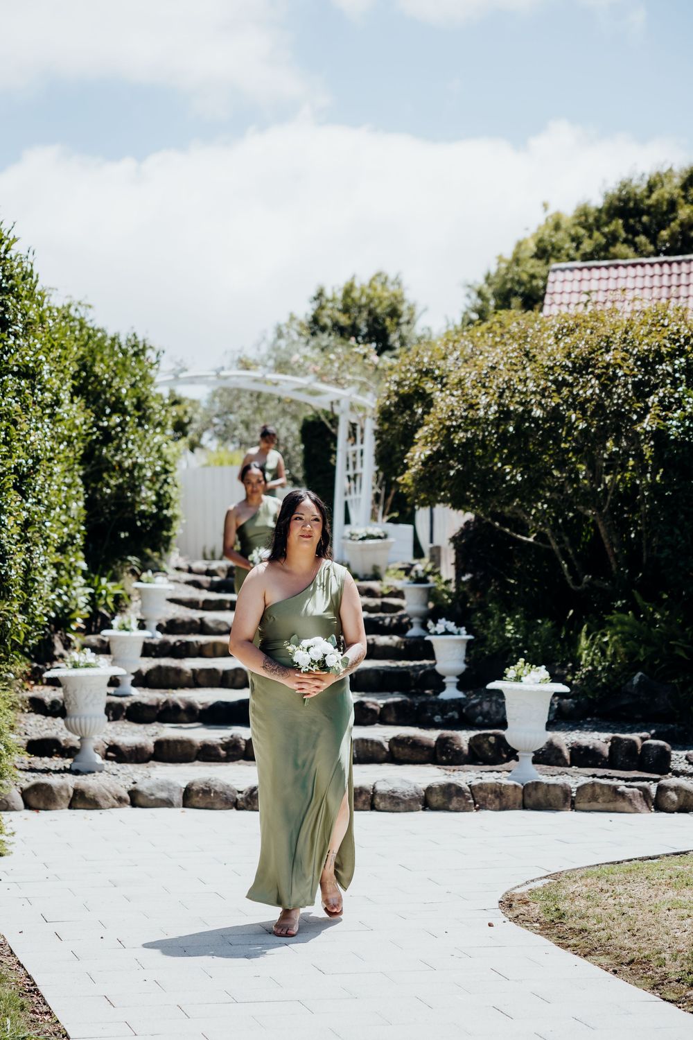 Wedding ceremony setup outdoors with white chairs and stone landscaping under a bright blue sky.