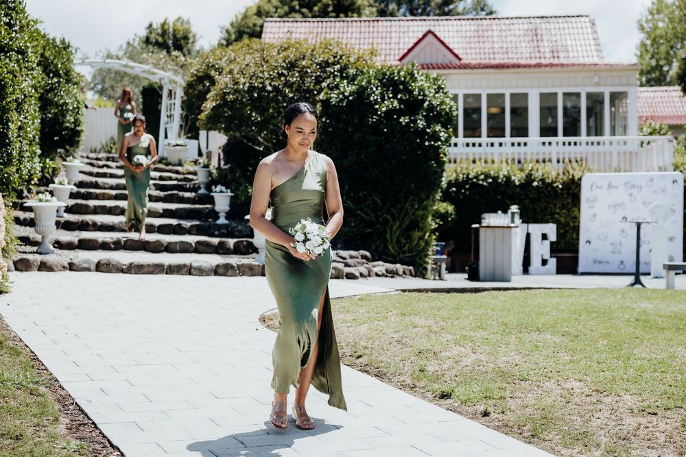 Outdoor wedding ceremony setup with white chairs and floral arrangements on a sunny day.