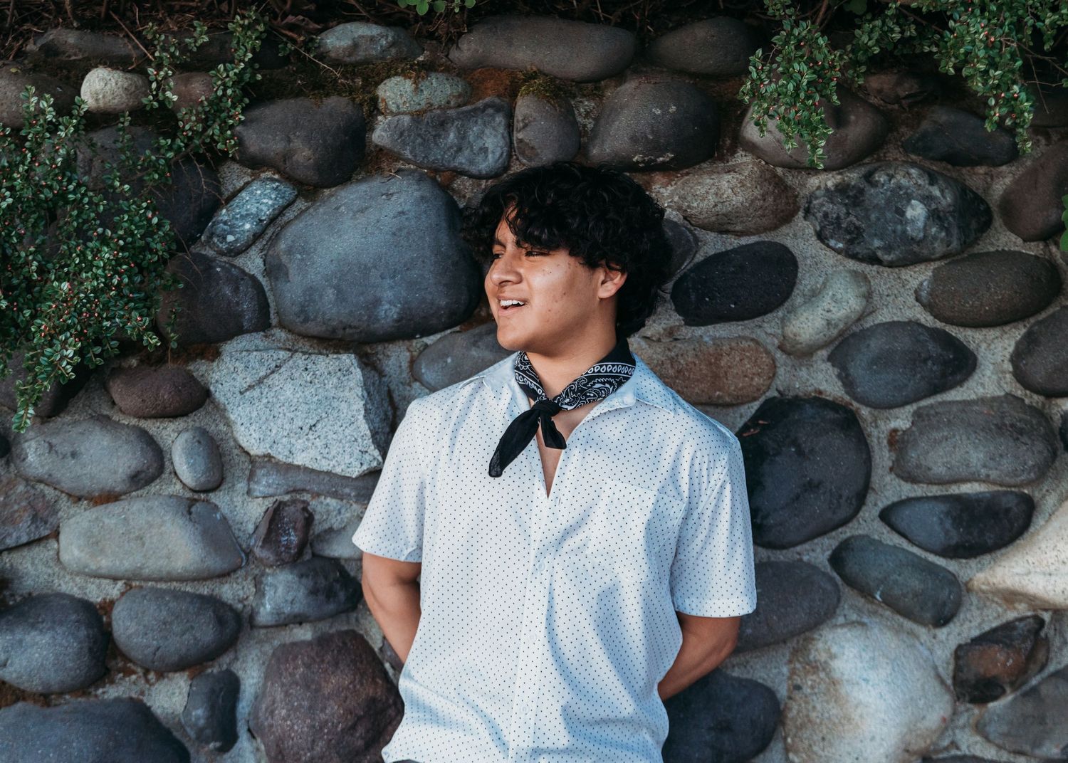 A series of casual portrait photos against a rustic stone wall showing someone in a white button-down shirt.