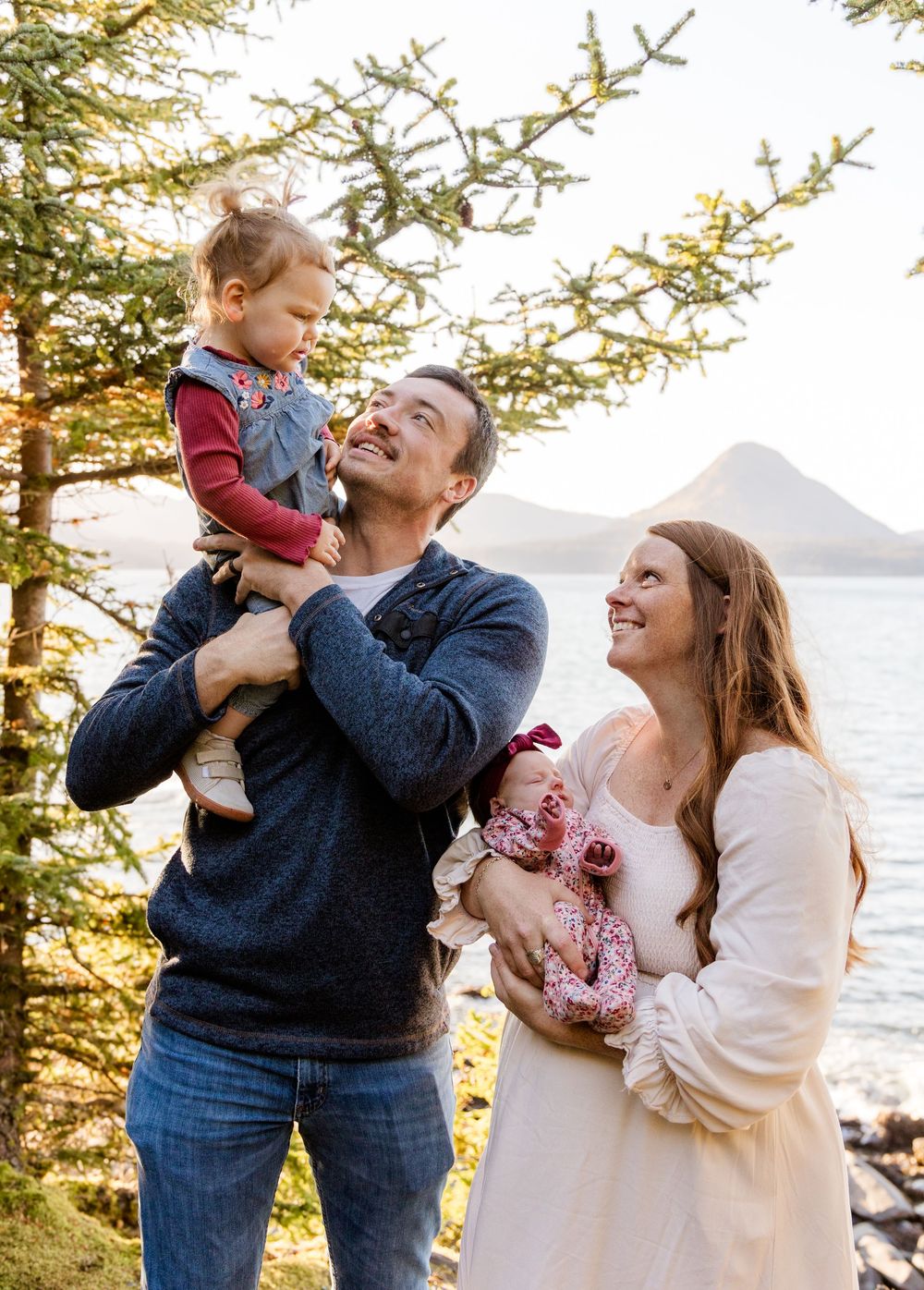 A family shares joyful moments together against a scenic coastal backdrop during golden hour.