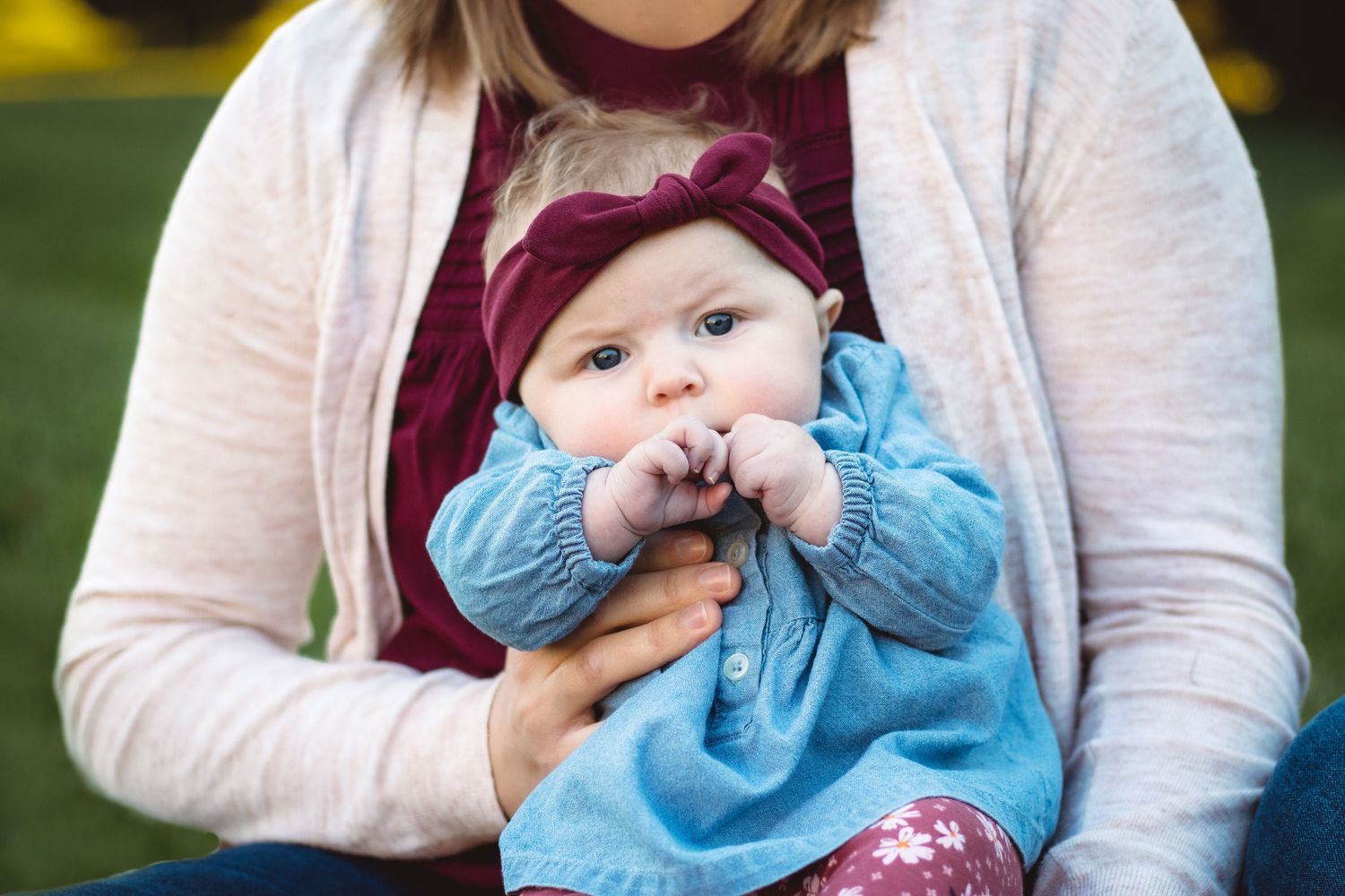 Mom holding baby with hands in mouth during family photo session in Metro Detroit, Sam Jackson Photography