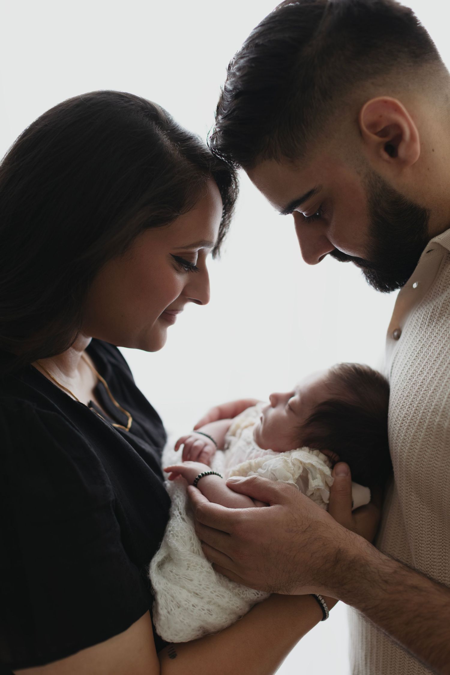 A series of intimate photos showing parents lovingly gazing at and cradling their newborn baby.