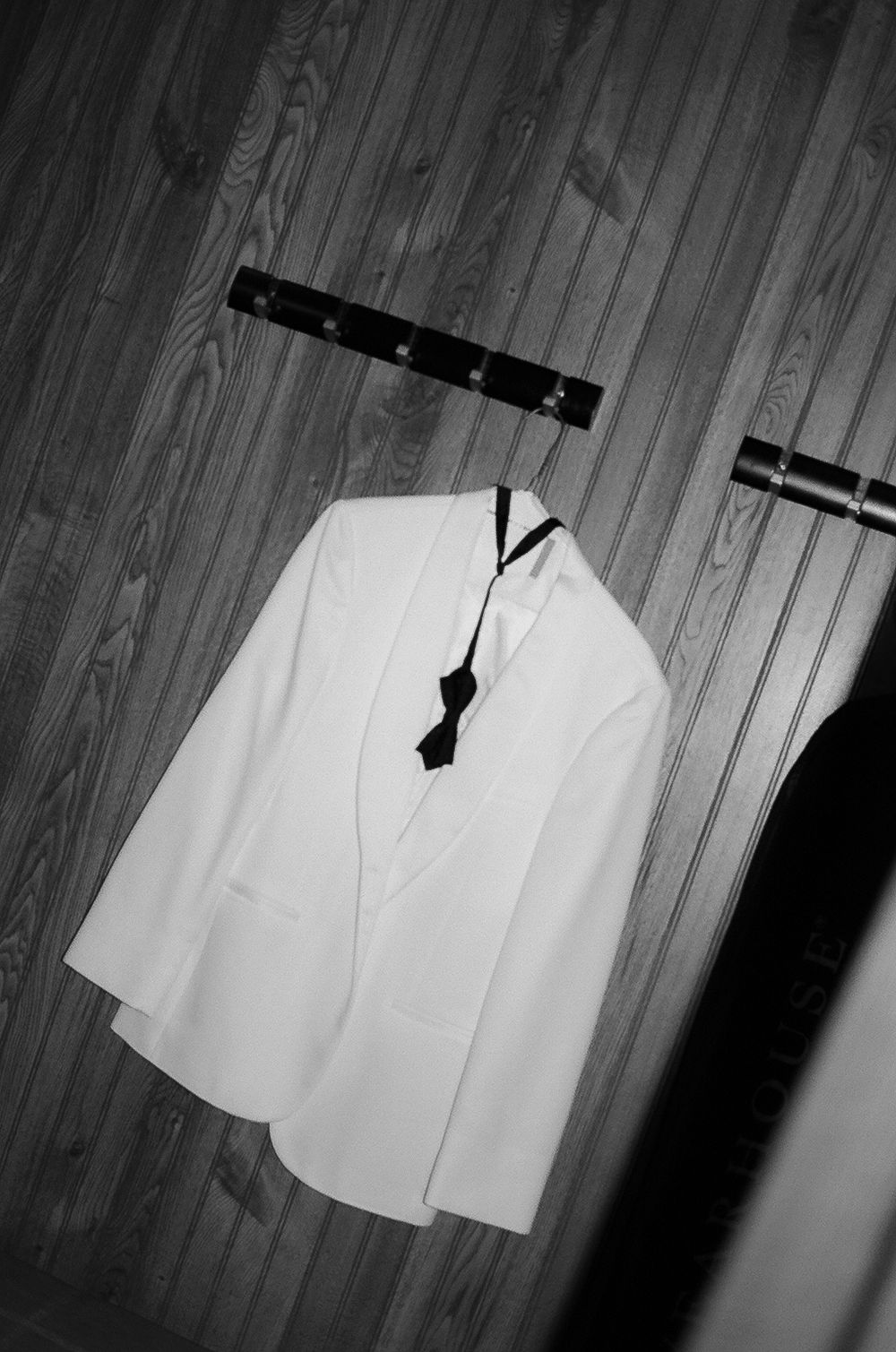 White sleeveless top hanging on wooden hangers against a dark background, shown from multiple angles.