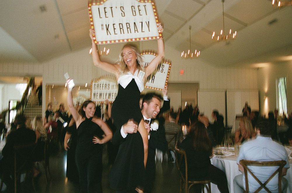 Wedding guests dancing and celebrating on a lively dance floor under elegant chandeliers.
