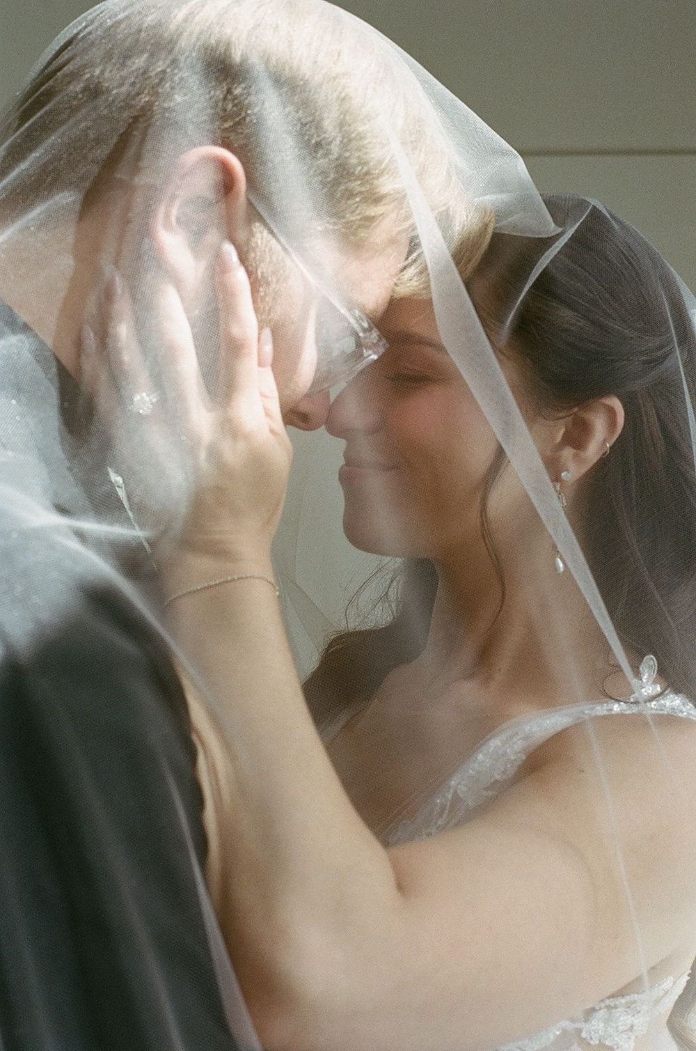 Romantic moment between newlyweds sharing a tender kiss under a delicate white veil.