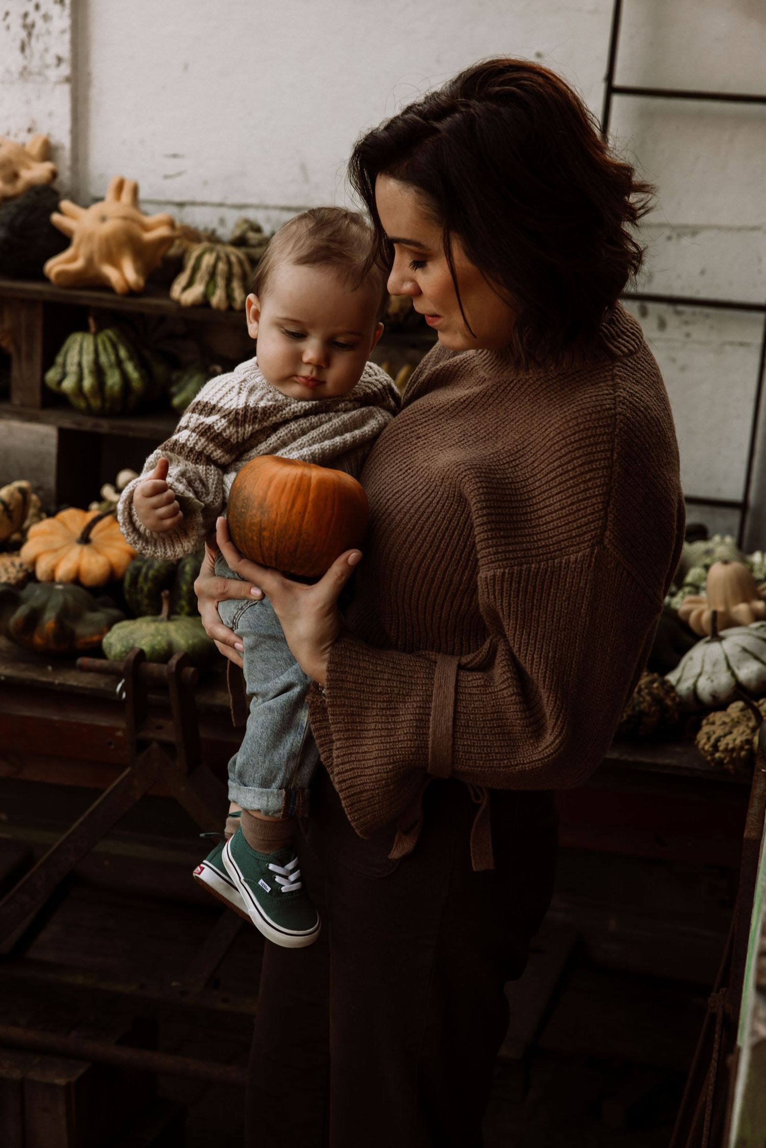 Autumn scene with brown sweater against rustic wooden backdrop with pumpkins and gourds.