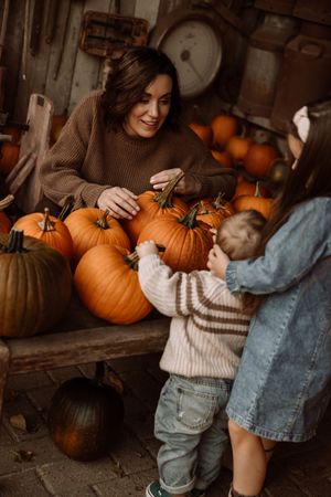 Cozy autumn scene with pumpkins and people in sweaters in a rustic setting.