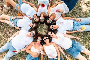 Group lying on grass in white shirts and jeans enjoying a summer day with red apples.