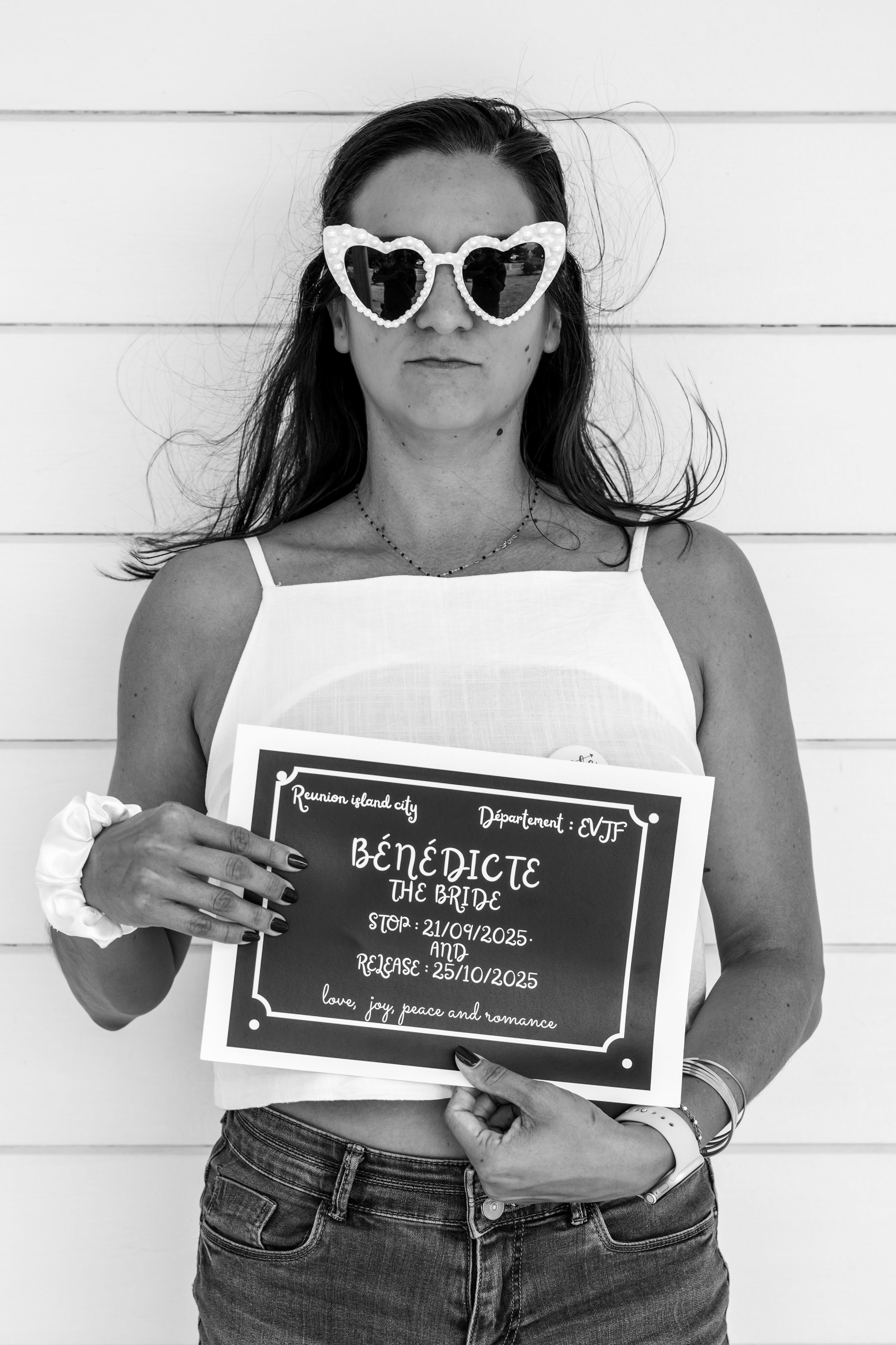 A black and white photo series showing three people holding chalkboard signs while wearing jeans and white tops.