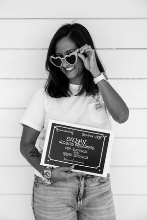 Black and white photo series showing someone in casual wear holding chalkboard signs with joyful expressions.