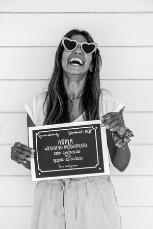 Candid black and white shots of person laughing while holding sign against white backdrop.