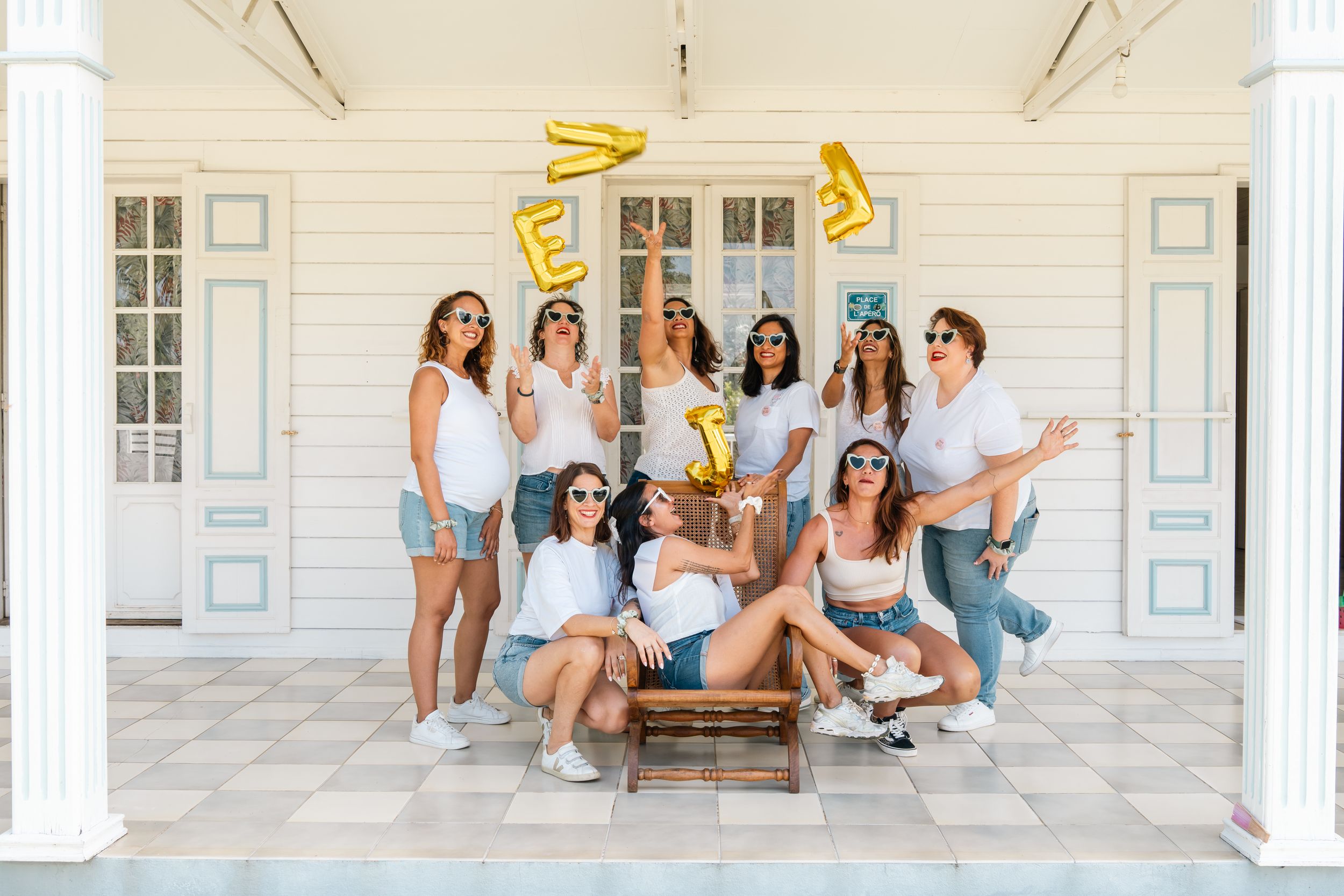 A group of friends enjoying summer weather while sitting and laughing together on a white porch.
