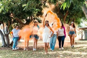 A group of people walk in a line outdoors while orange smoke creates a dramatic effect behind them.