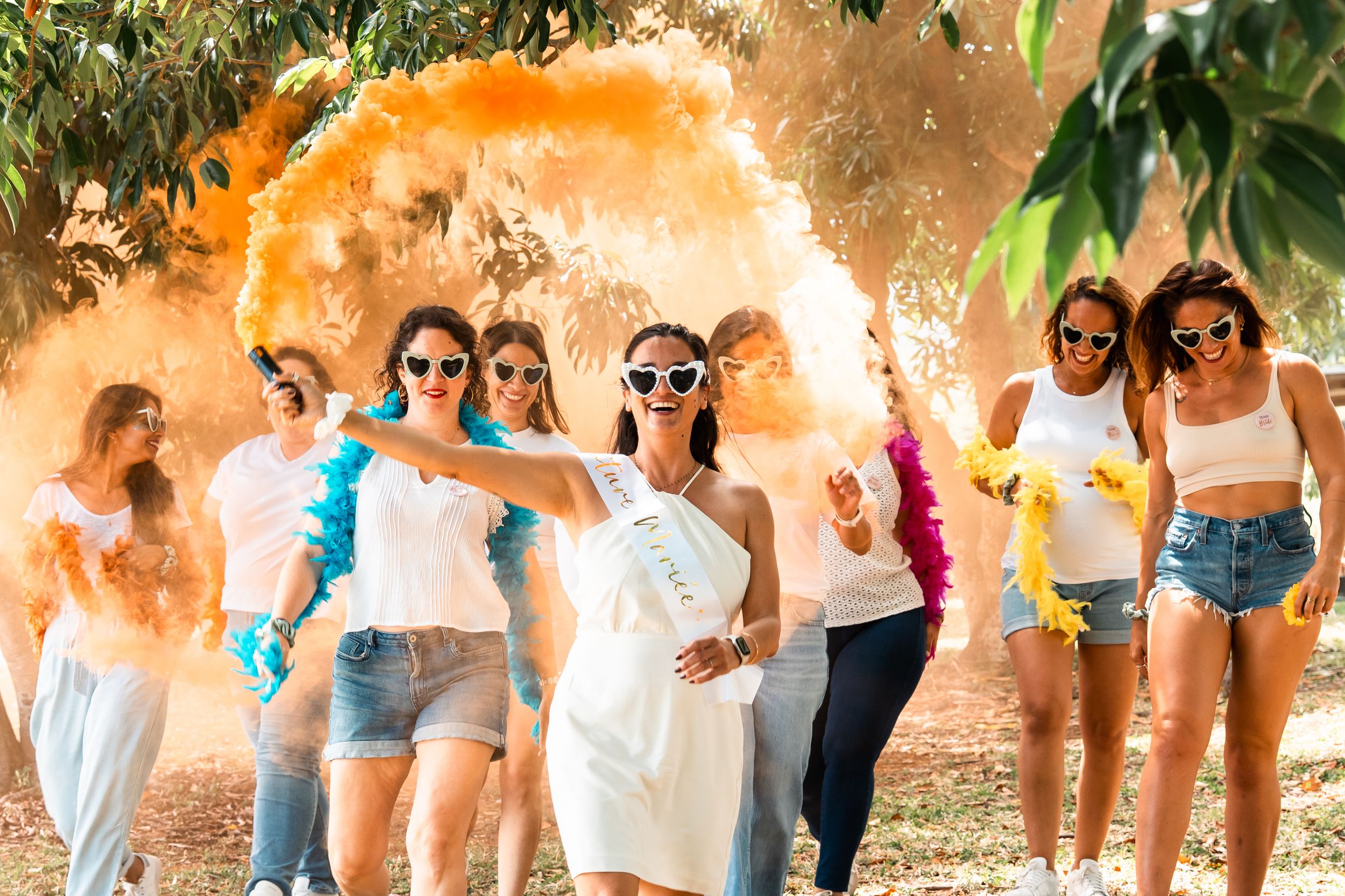 A group of people dancing and celebrating outdoors with colorful powder explosions creating a festive atmosphere.