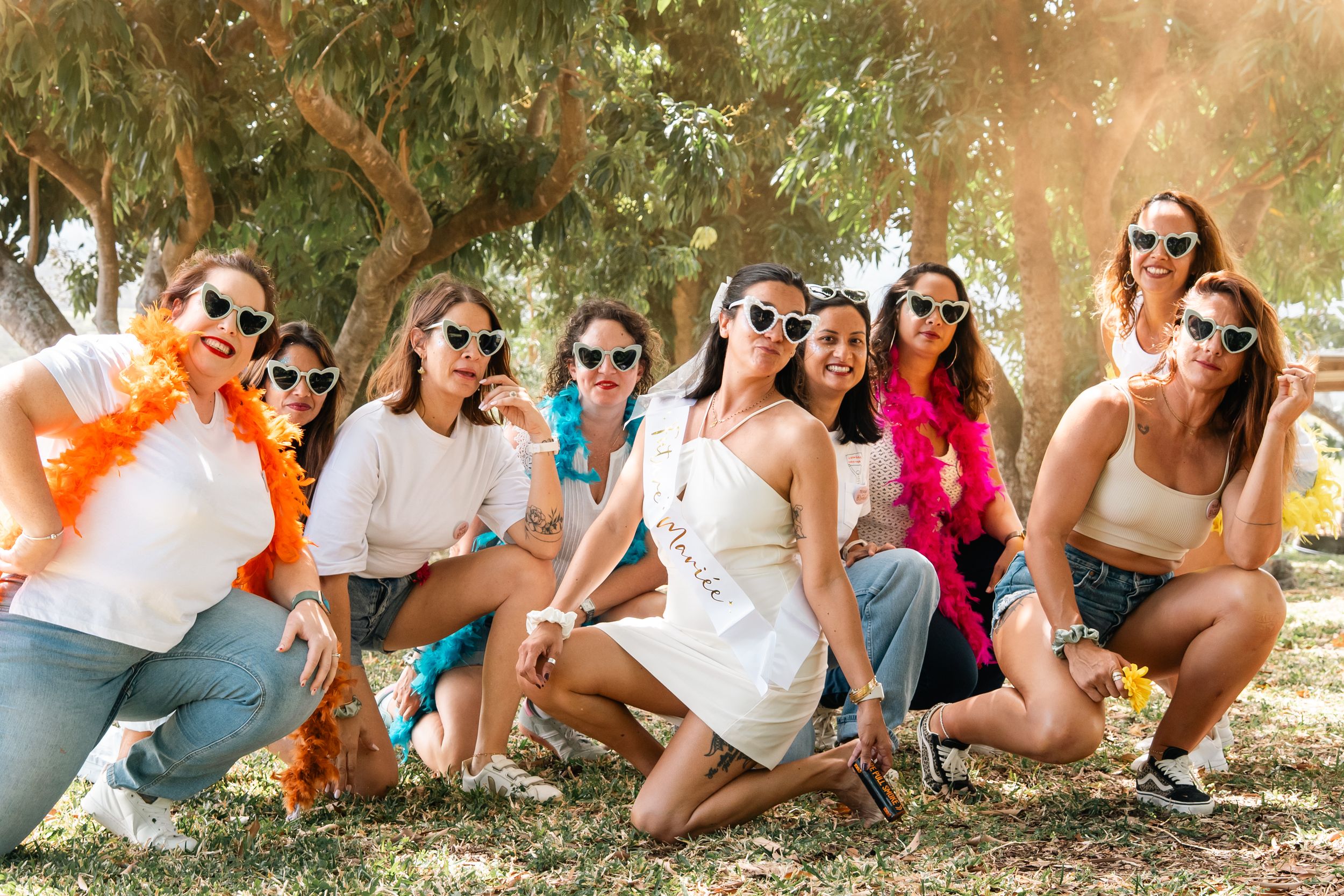 A group of friends wearing sunglasses lounge together on grass in a fun summer photo shoot sequence.