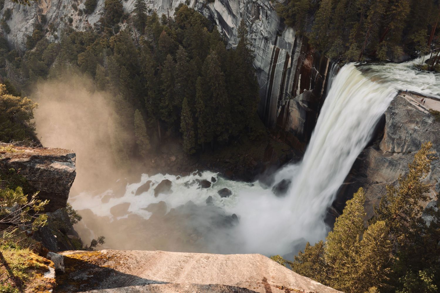 Dramatic aerial view of a powerful waterfall cascading through forested cliffs.