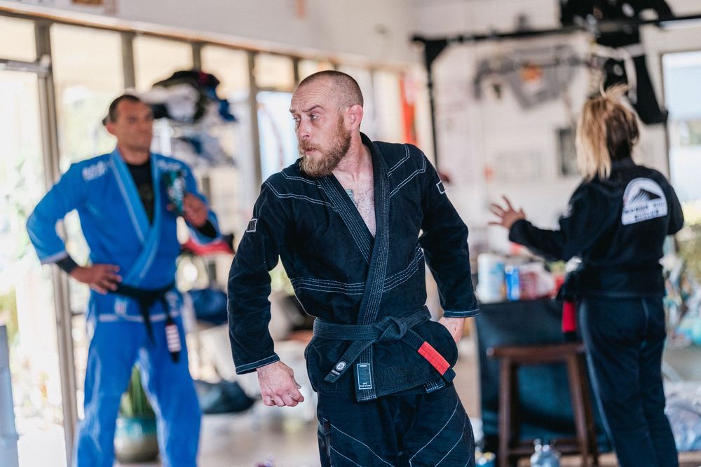 Students practicing martial arts techniques in a training studio with blue mats and white walls.
